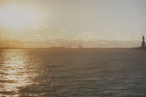 Sunlight reflects on the water across from the Statue of Liberty