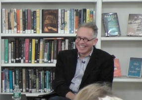 Dan Frank laughing in front of a bookshelf