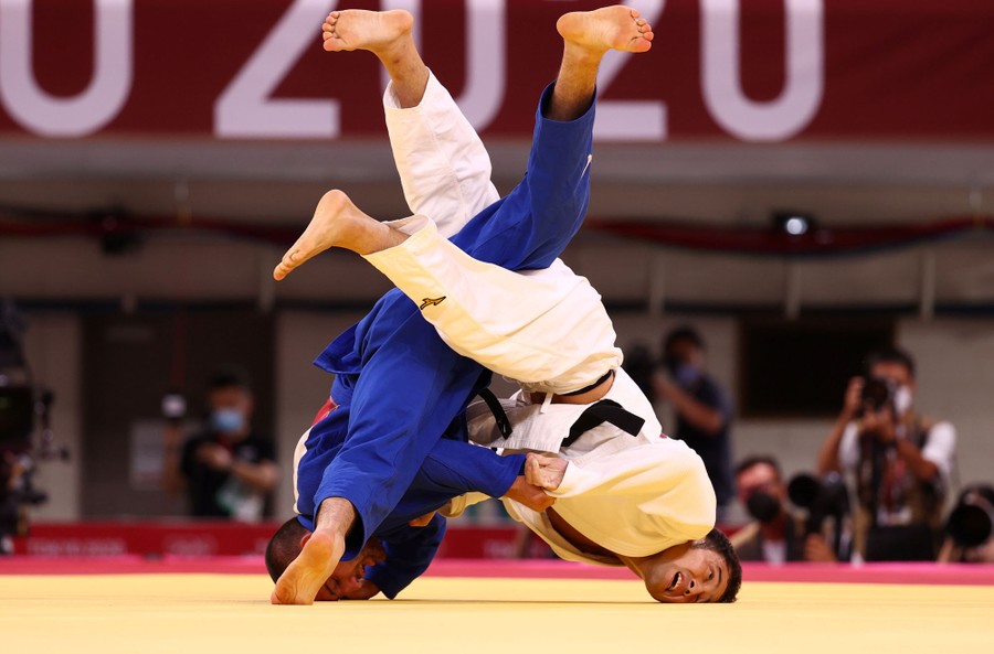 Competitors grapple upside-down during a judo match.