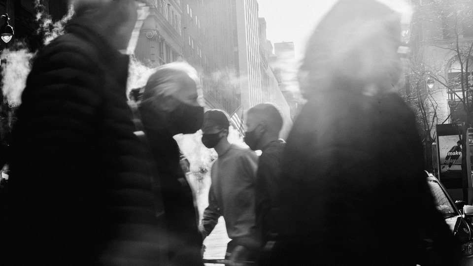 An American flag is seen through a crowd of people crossing the road on December 13, 2020 in New York City.