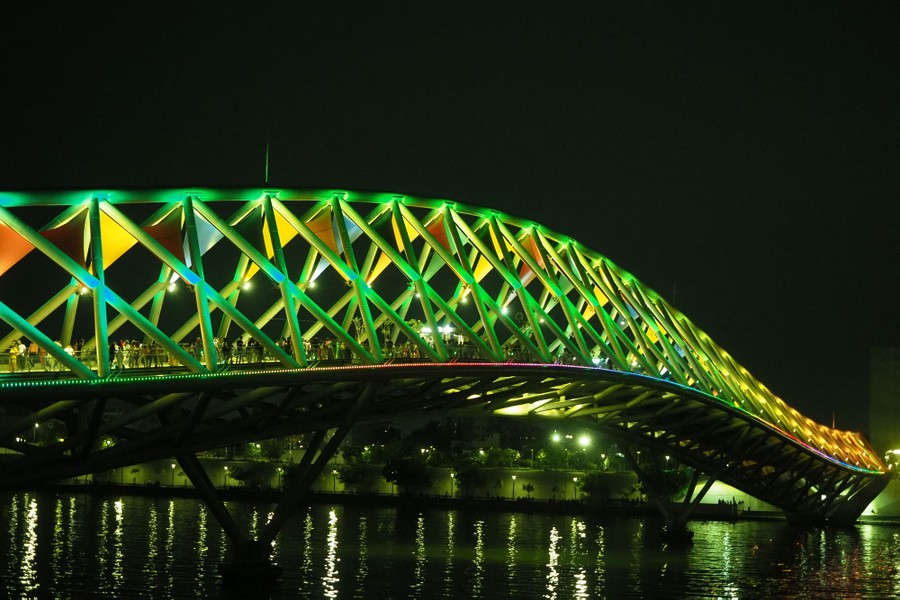 A curving pedestrian bridge is lit up at night.