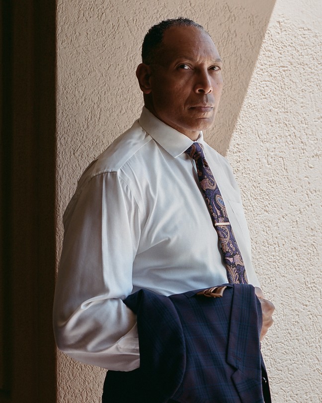 Ben Spencer in a suit staring at the camera