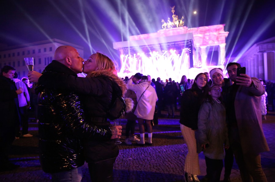 People in a crowd embrace as a light show happens in the background.