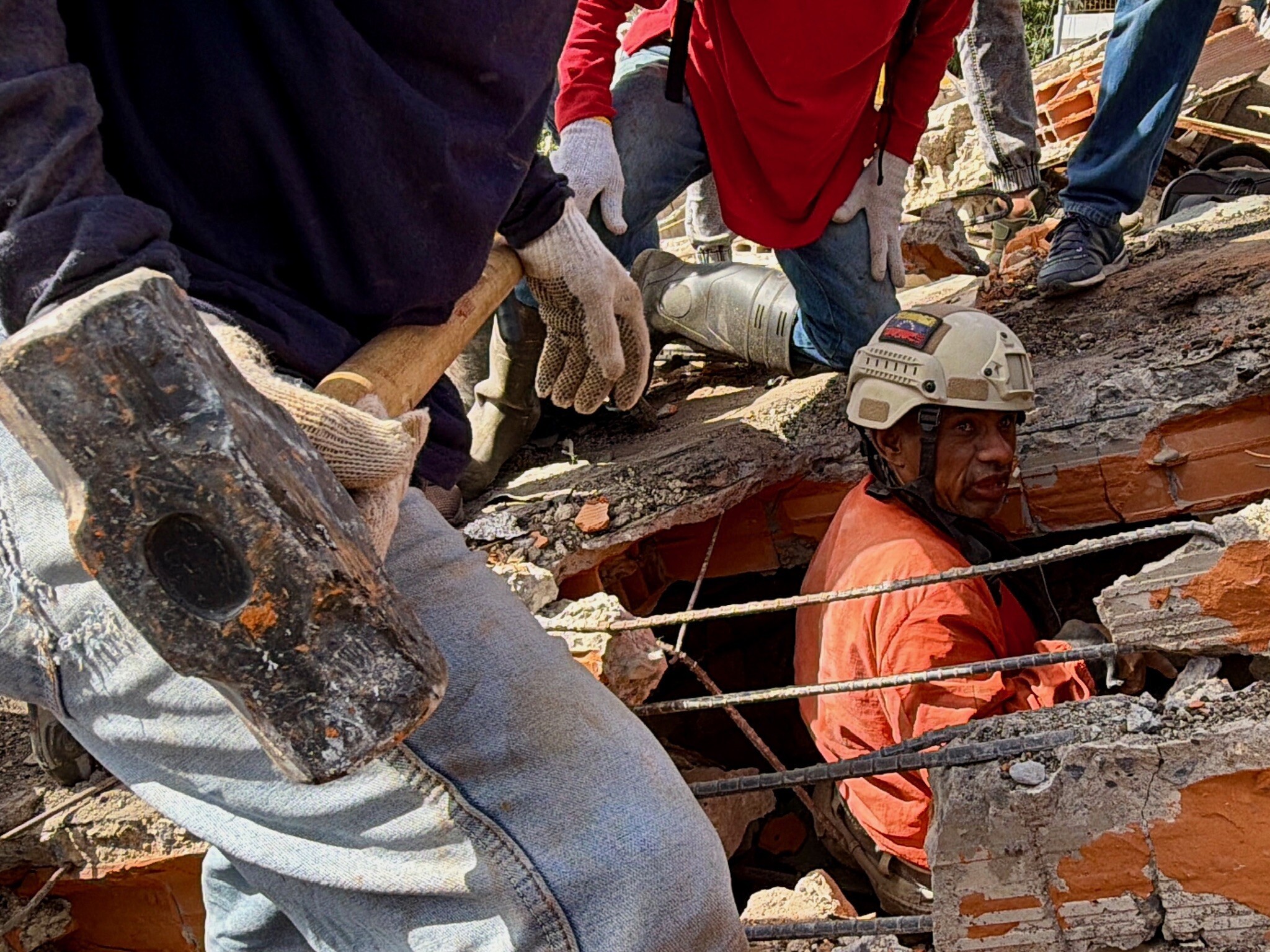 One rescue worker holds a sledgehammer as others work to search inside the rubble of a collapsed building.