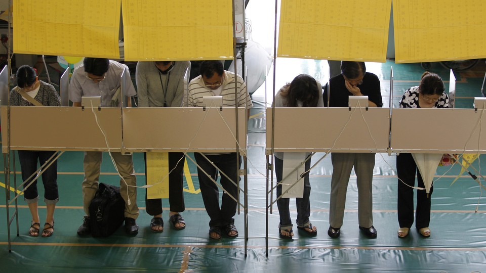 Voters fill out ballots for Japan's upper house election at a polling station in Tokyo on July 11, 2010.