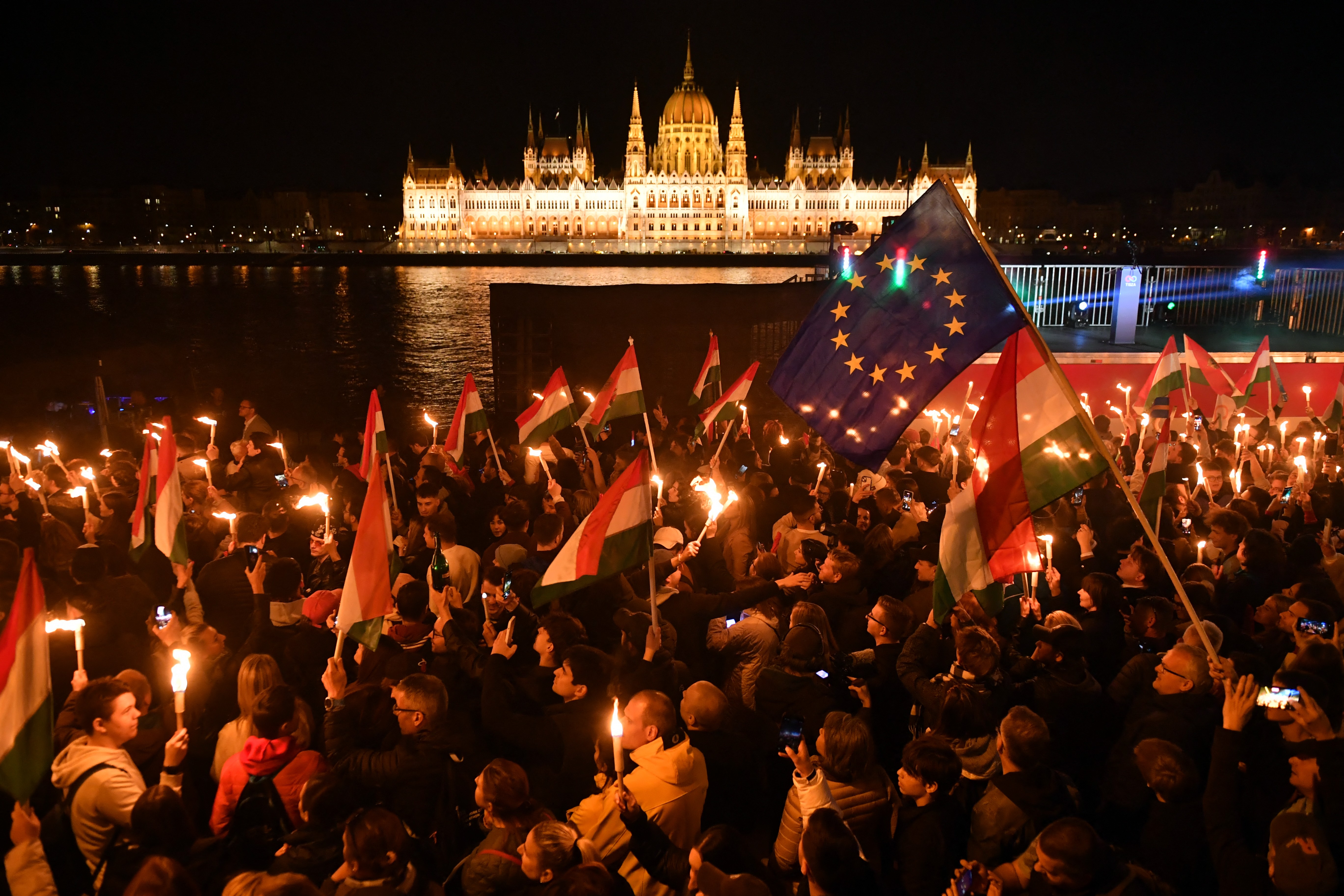 People celebrate during election night on the banks on the river Danube with Hungary's Parliament building in the background.