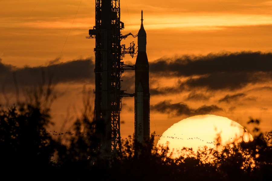 A sunrise view of a tall rocket and support tower