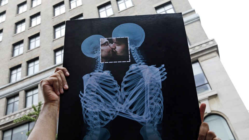 A couple kisses behind an X-ray poster.