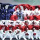 Kendrick Lamar and dancers dressed in red, white, and blue form the shape of an American flag during a performance.