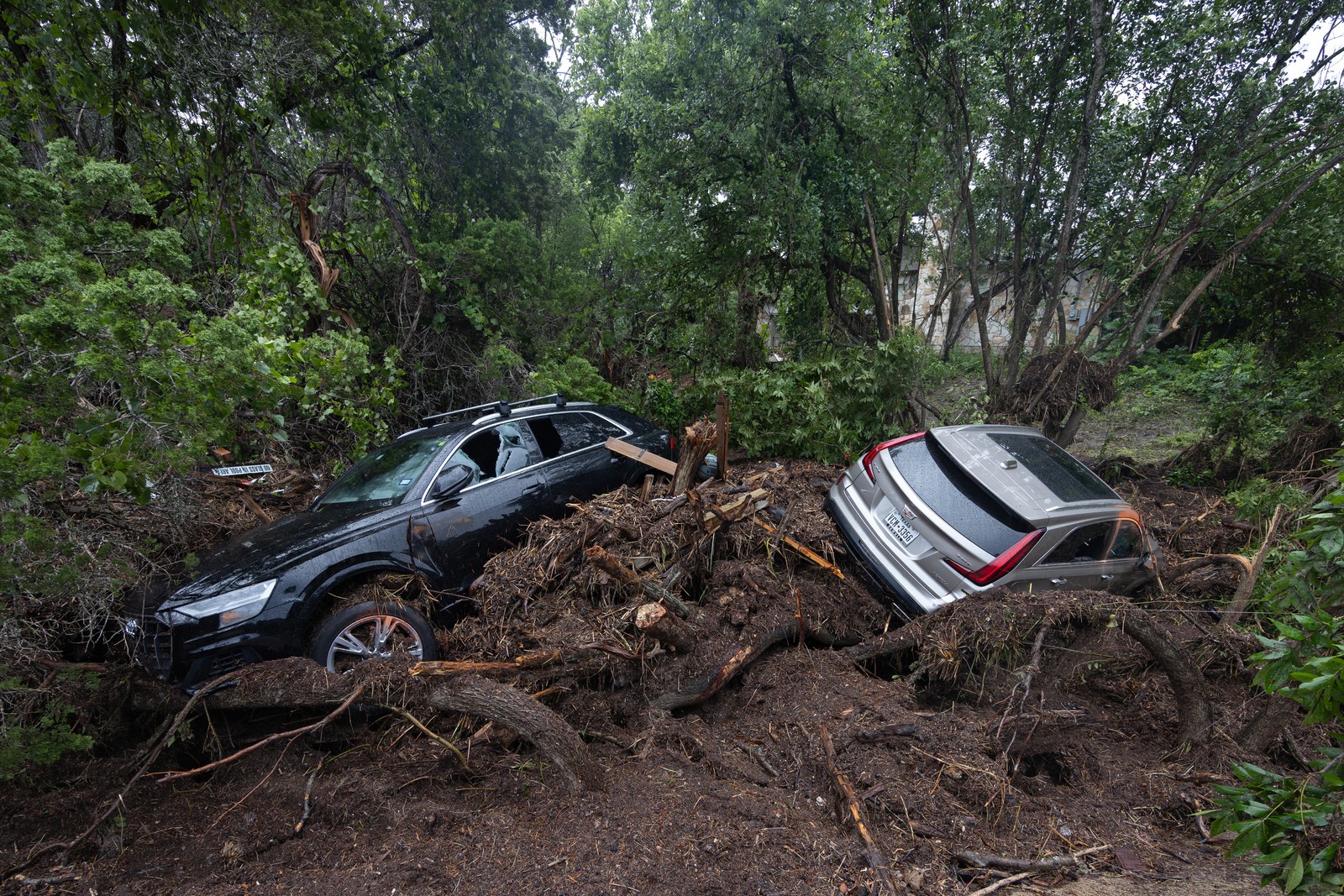 Two ars that were swept away by flooding sit in piles of debris.