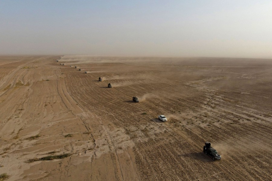 An aerial view of a long line of military vehicles driving through a desert
