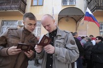 Men look at their new Russian passports after receiving them at a federal office in Simferopol, Crimea, in 2014.