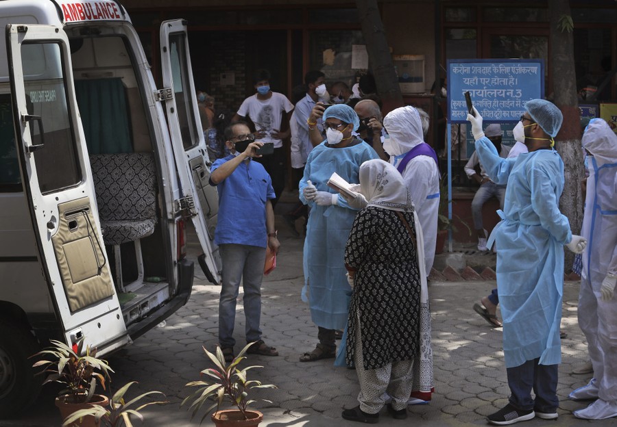 People gather to say last rites near the back door of an open ambulance.