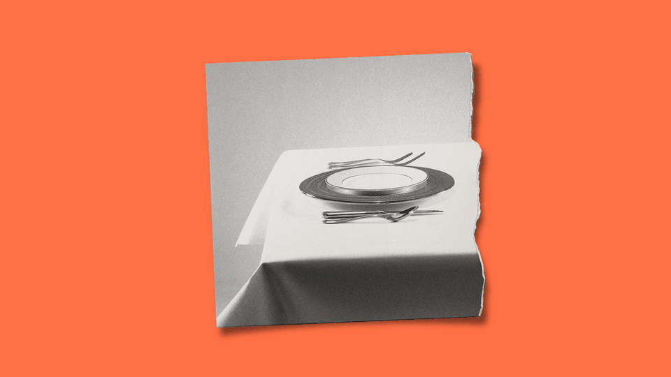 A ripped photograph of a dinner table, showing a plate and utensils set for one