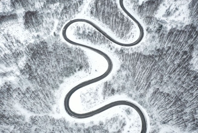 A drone photo shows a view of snow-covered trees and a twisting highway between Kutahya's Domanic and Bursa's Inegol districts in Bursa, Turkey, on January 18, 2022. 