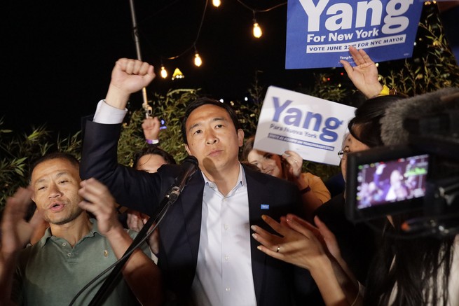 Photograph of Andrew Yang surrounded by supporters at a campaign event with a raised fist