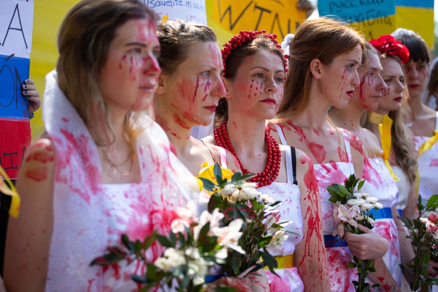 About a half-dozen women are seen during a protest wearing white dresses and covered in splashes of fake blood.