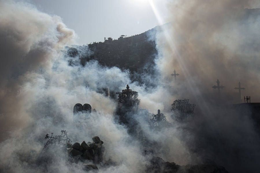 Fumigation clouds swirl around headstones in a graveyard.