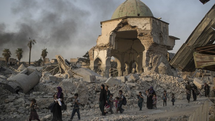 Fleeing Iraqi civilians walk past the damaged al-Nuri mosque as Iraqi forces continue their advance against ISIS militants in Mosul on July 4, 2017.