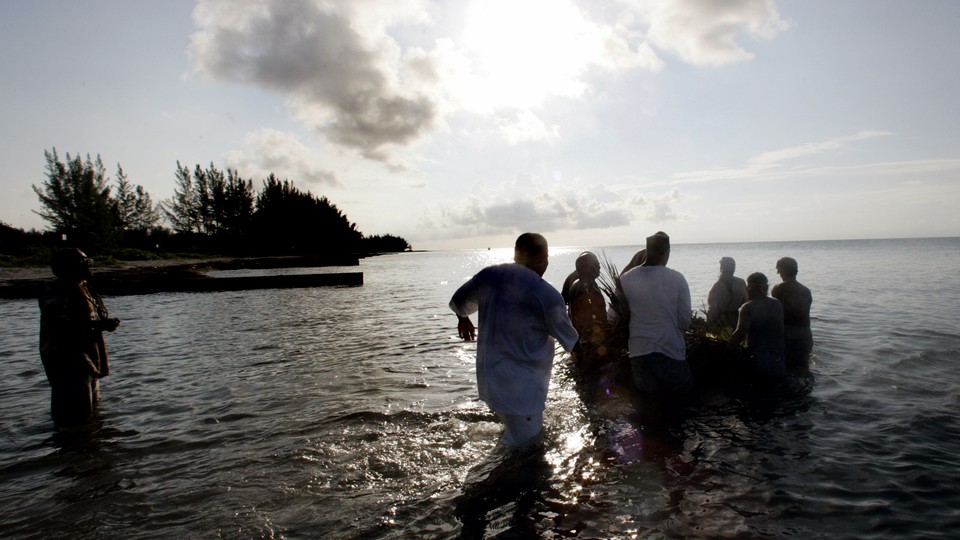 A group of men wade into the ocean as part of a Juneteenth ceremony
