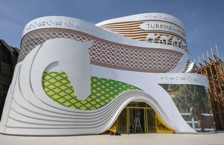 The Turkmenistan pavilion, with curved walls decorated by swooping lines that form the mane of a large horse's head