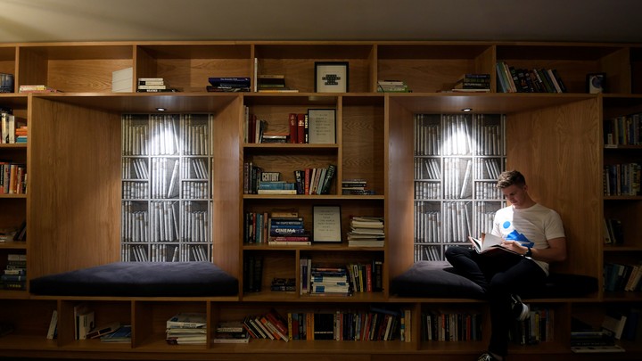 Man reads next to bookshelves