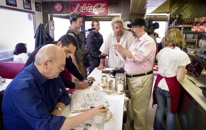 During a break in shooting, producer of the Food Network program, "Diners, Drive-ins and Dives," David Page, hat, talks with host Guy Fieri, center, while filming a segment on Brint's Diner in south Wichita, Kan., for an upcoming show, Thursday, March 1, 2007. 