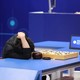 A man slumps in defeat over a Go board.