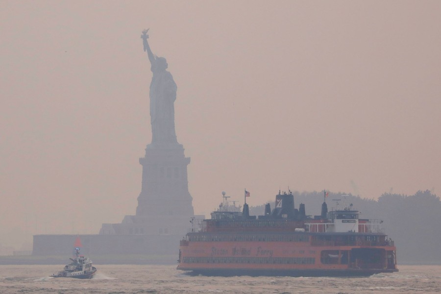 A ferry moves past the Statue of Liberty on a hazy day.