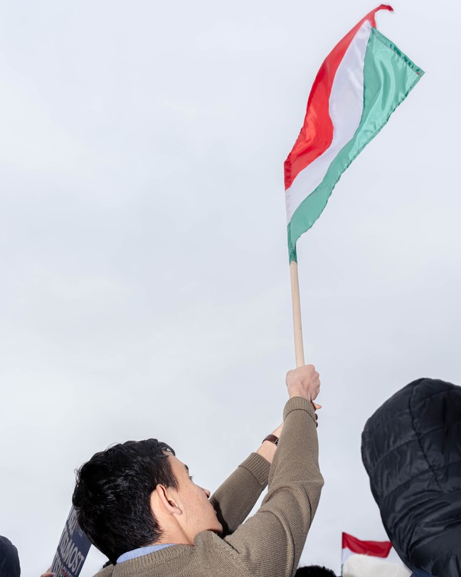 Man at a rally holding the Hungarian flag