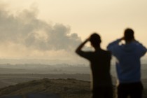 People looking at smoke over the Gaza Strip