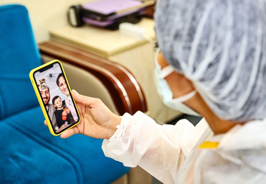 A health-care worker speaks with their family over video.