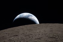 A photo of the Earth in a crescent shape, with the dark side of the moon in the foreground.