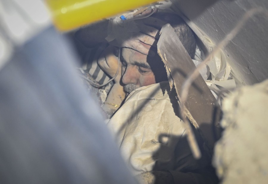 A view of a person trapped in rubble, a hand held to their head