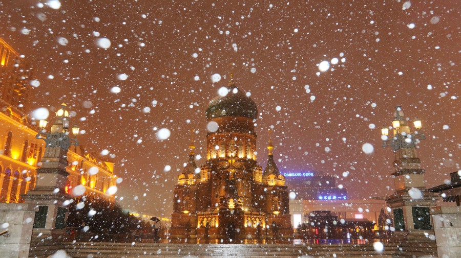 Snow falls at night in a Chinese city.