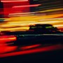 A blurry photo of a pickup truck driving at night amid city lights