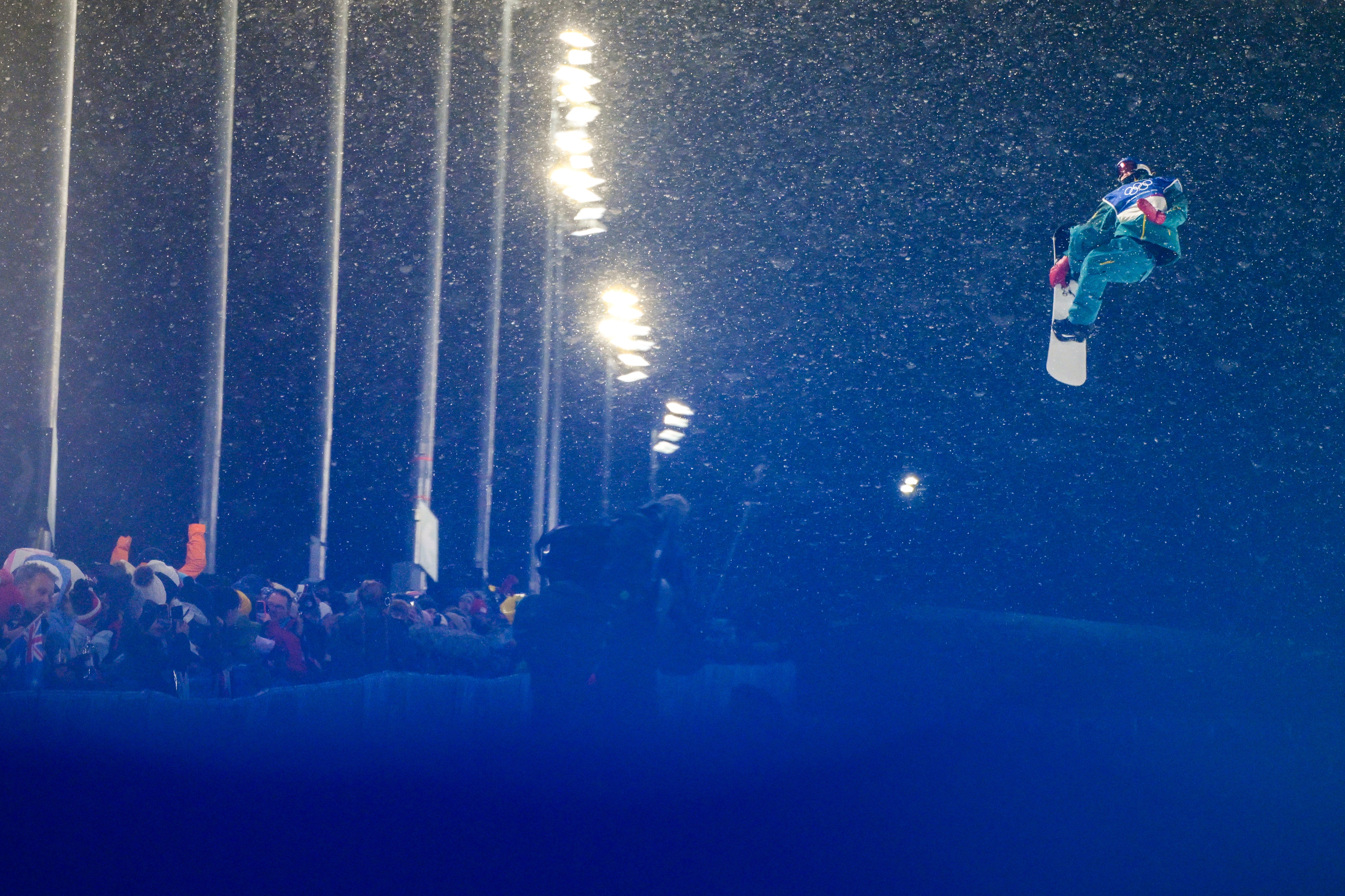 A snowboarder flies high during a jump, seen in a blue-tinged image.