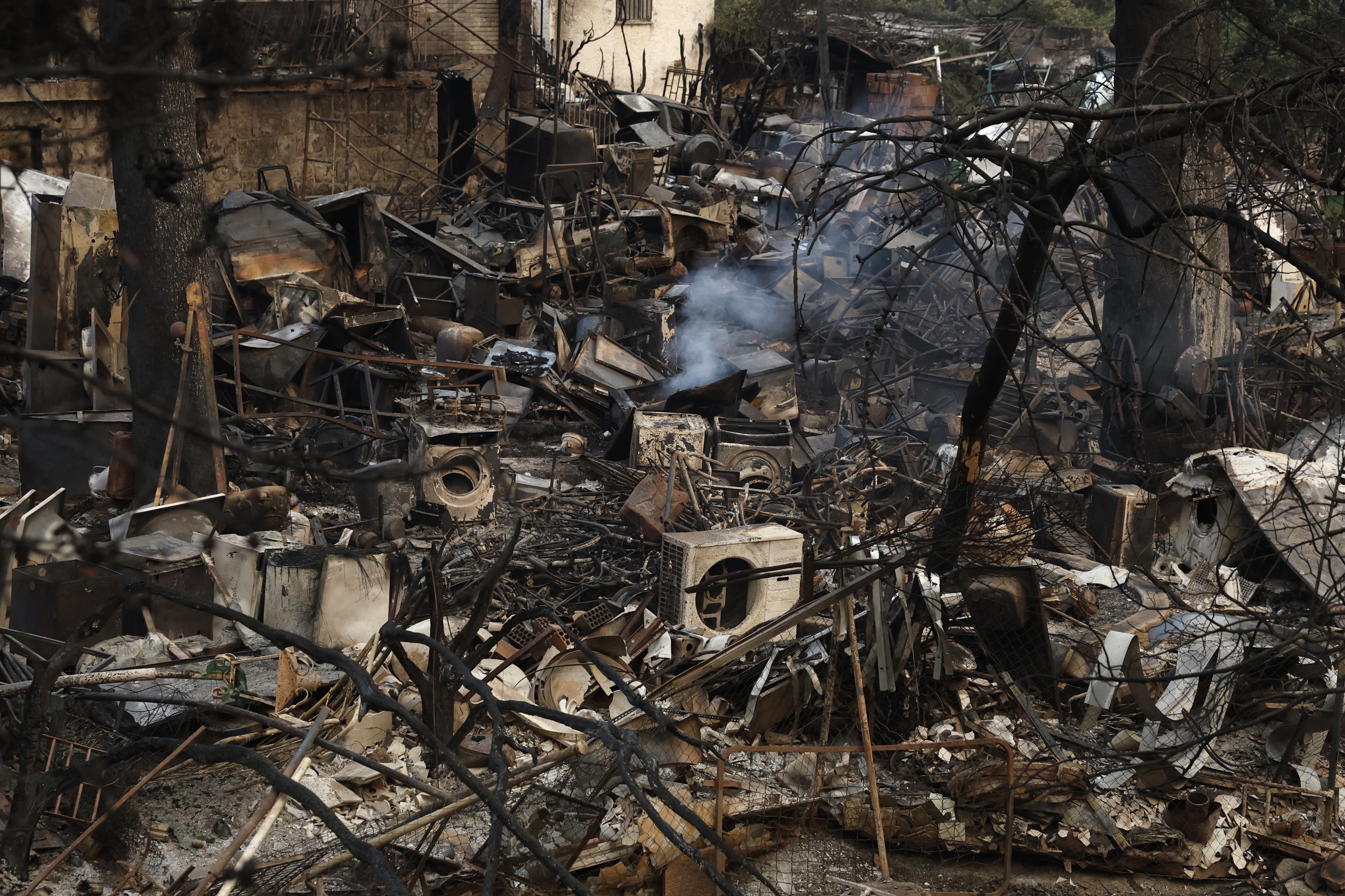Smoke rises from a plot used for storing scrap metal, with scorched metal and machinery strewn about.