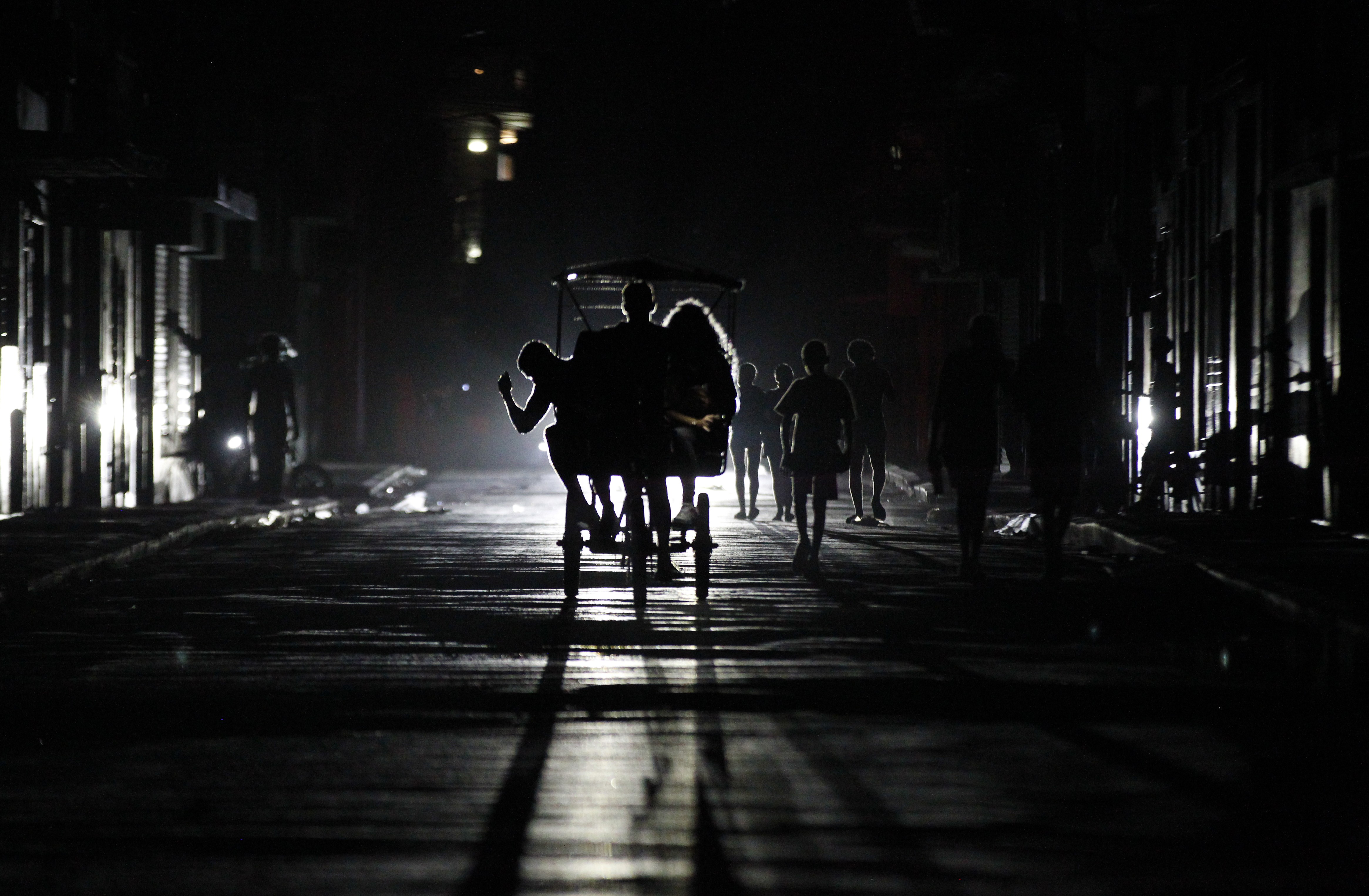 People ride a pedal taxi at night during a blackout.