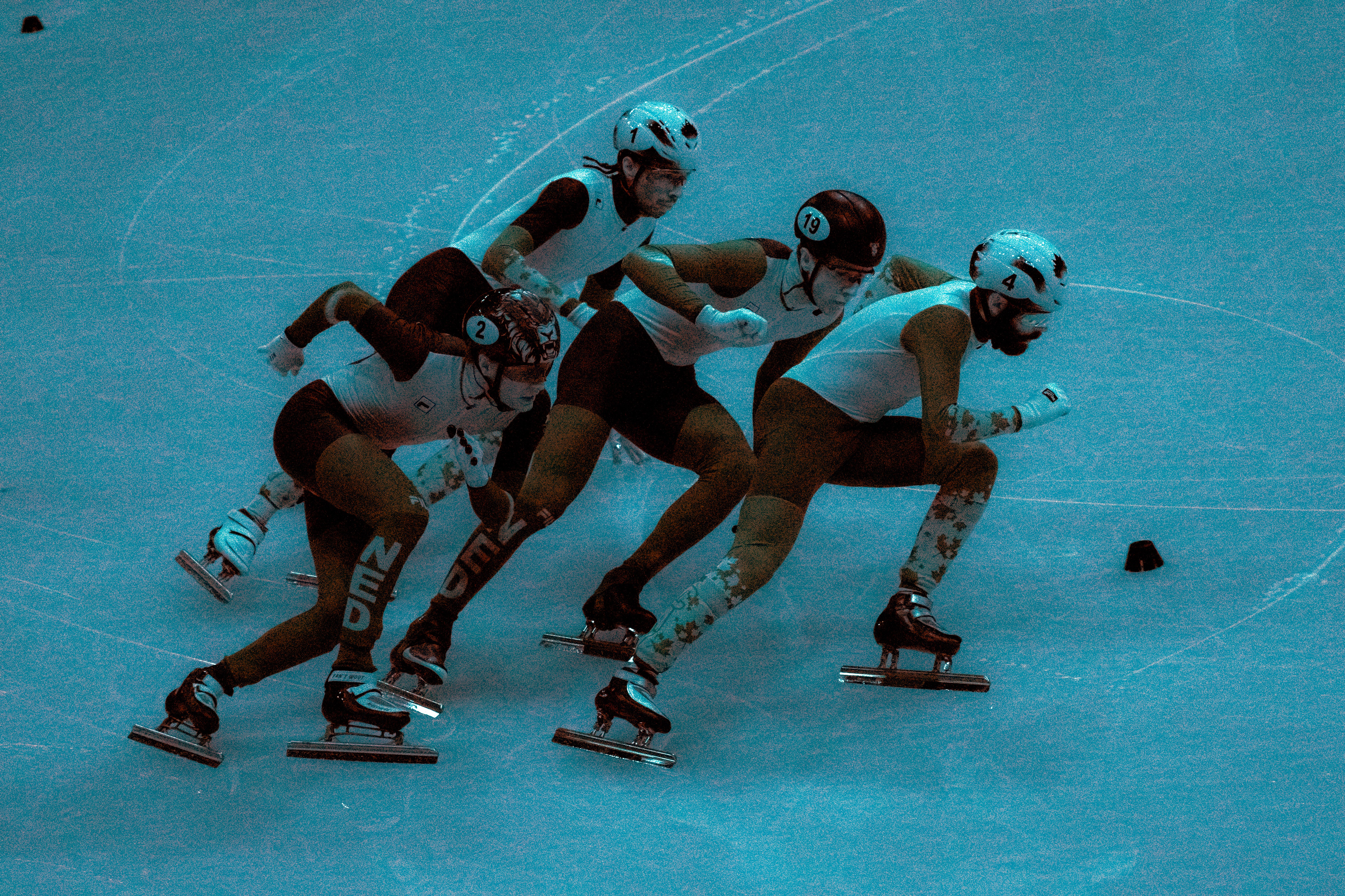An infrared image of racing speed skaters washes everything in a bluish color.