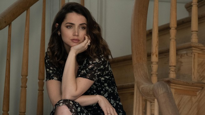 Ana de Armas gazing into the distance while sitting on a staircase in "Deep Water"