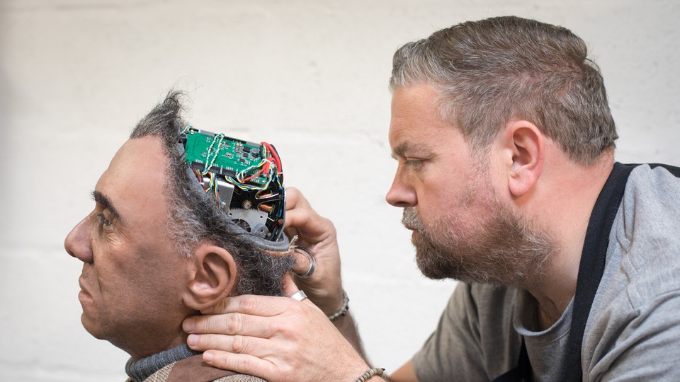 A human fixes a human-looking robot
