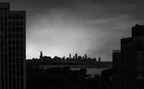 Black-and-white photo of Chicago's skyline in the distance, framed by other buildings in the foreground