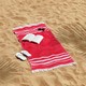 A red towel with a book, flip flops, and sunglasses on the beach