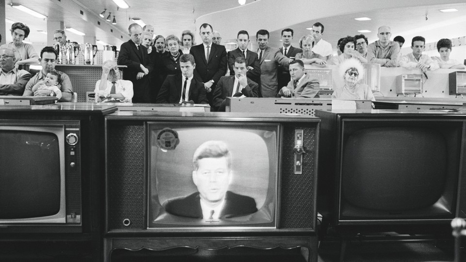 Customers in the electronics section of a department store watch as JFK addresses the nation