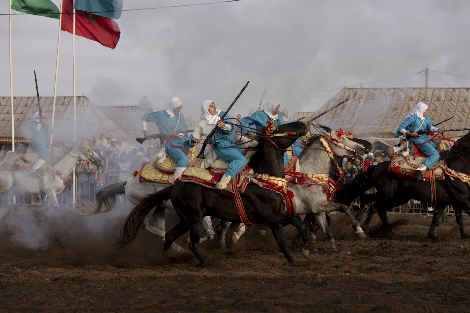 A troupe of women carry and fire rifles on horseback during a performance.