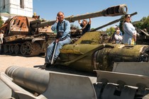 A man sits on a Russian missile displayed for Ukrainians in central Kyiv.