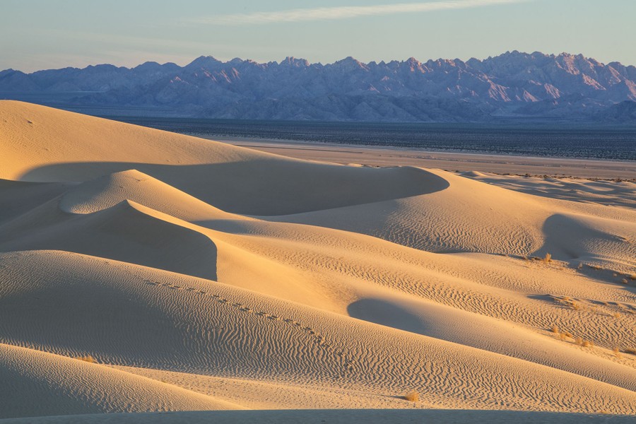 Small sand dunes stand before a distant mountain range.