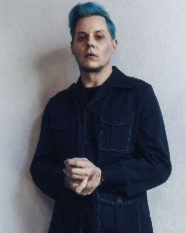 soft-focus photo of Jack White with blue hair wearing dark collared shirt and clasping hands together