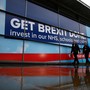 People walk past a Brexit sign outside the venue for the Conservative Party annual conference in Manchester, Britain.